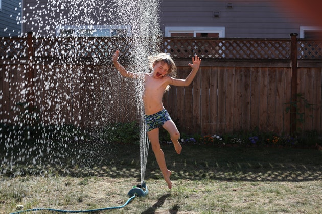 boy running through sprinkler